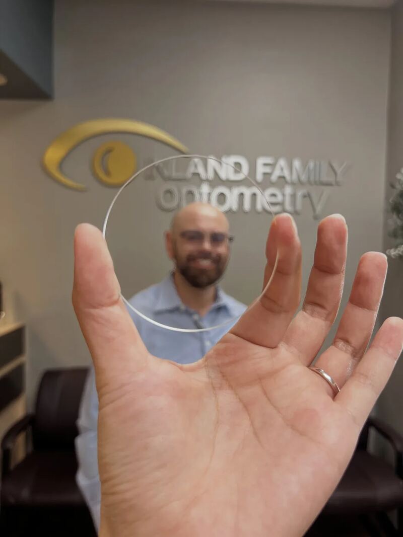 A clear optical lens held in front of an Inland Family Optometry team member